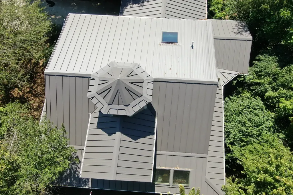Standing seam panels meeting at an octagonal cupola — the seam is folded closed and no fastener touches the panel face