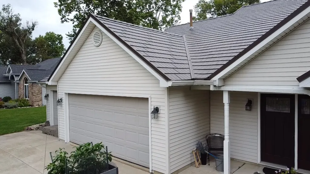 Warm grey metal shingle roof over a home's front gable and garage